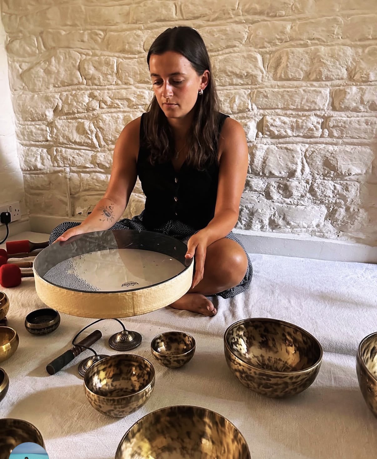 Keira seated with singing bowls and a large drum